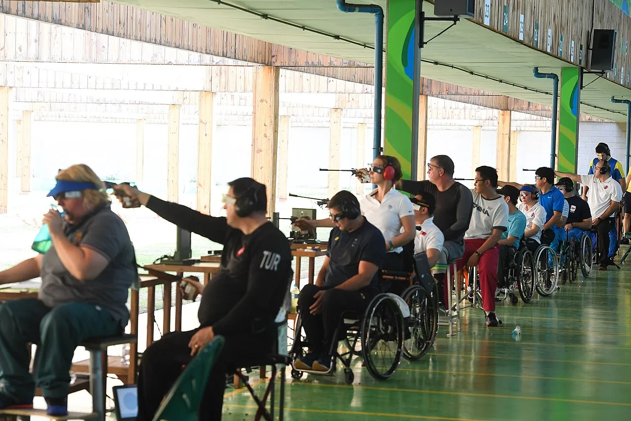 Linea di tiro paralimpica con atleti in carrozzina e su sgabello alto